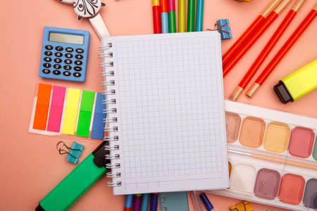 School notebook and various stationery on pink