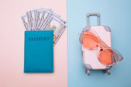 Travel luggage suitcase with sunglasses and passport with money on blue pink background. Summer vacation conceptの写真素材