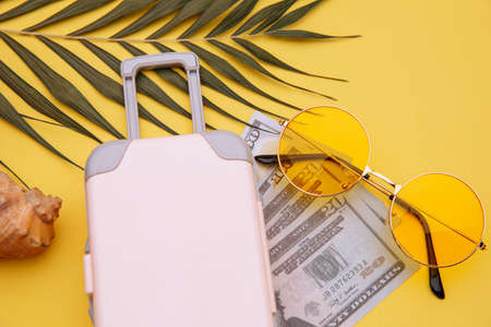 Travel luggage suitcase and sunglasses on yellow background close-up. Travel, summer vacation or tourism conceptの写真素材