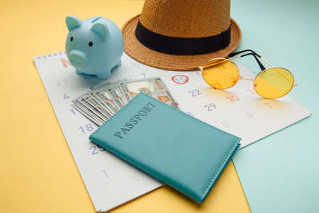 Summer Calendar Schedule with passport, sunglasses and piggy bank on blue yellow background. Travel, tourism, holiday conceptの写真素材
