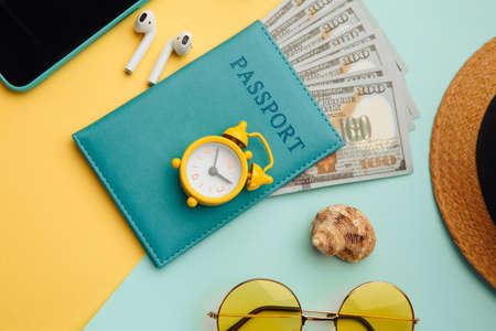 Tourism concept. Sunglasses, smartphone, hat and passport on blue yellow background close-upの写真素材