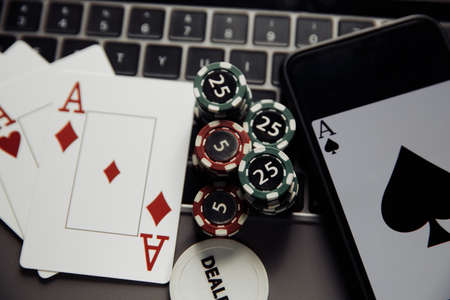 Online poker casino theme. Close-up gambling chips, smartphone and playing cards on keyboard