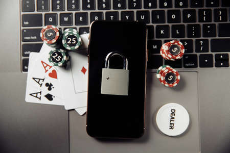 Law and rules for online gambling concept, smartphone with padlock and playing chips on keyboard