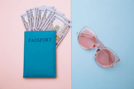 Pink sunglasses and passport with money on blue pink background. Travel, summer vacation or tourism...