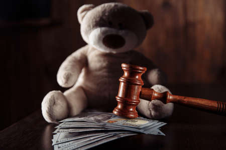 Payments alimony. Wooden judge gavel, dollar banknotes and teddy bear close-up. Divorce and separation conceptの写真素材