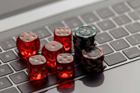 Online casino concept. Gambling chips and five red dices on laptop keyboard close-upの写真素材