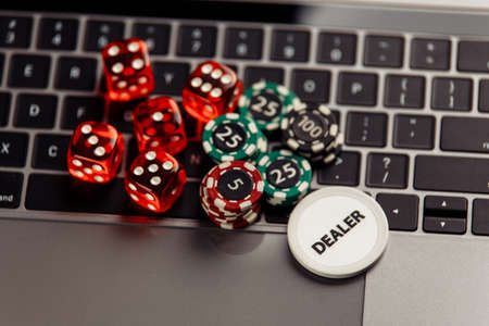 Online casino concept. Gambling chips and dices on laptop keyboard
