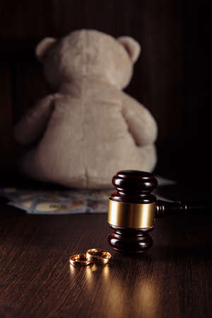 Alimony payment. Dollar banknotes, judge gavel with rings and teddy bear. Family divorce and alimony conceptの写真素材