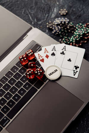 Online casino. Gambling chips, cards with aces and red dices on laptop keyboard. Vertical imageの写真素材