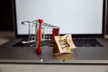 Damaged paper box and shopping cart on a keyboard of laptop. Delivery concept. Shipment accidentの写真素材