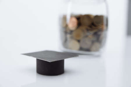 Hat graduation model close-up and coins in bank. Saving for education and scholarships