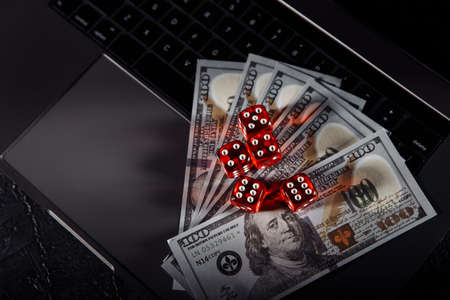 Dice and dollar banknotes on laptops keyboard. Online casino and gambling concept