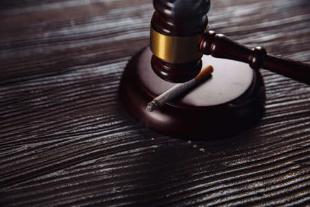 Smoking cigarette and wooden judge gavel close-up. Dangerous habbit