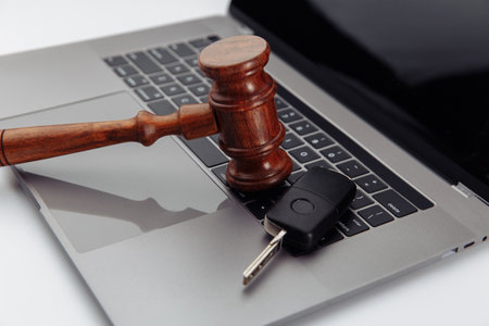 Judge gavel and car keys on laptop computer keyboard. Symbol of law, justice and online car auctionの写真素材
