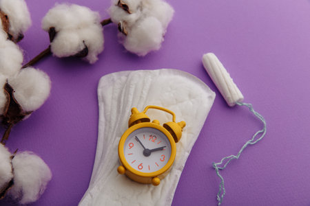 Daily sanitary pads, tampon and yellow alarm clock close-up. Hygiene protection for woman critical daysの写真素材