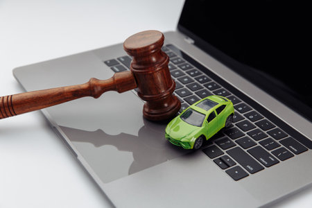 Judge gavel and toy car on laptop computer keyboard. Symbol of law, justice and online car auction.の写真素材