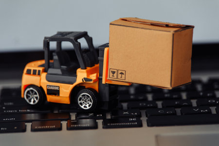Orange forklift model and carton box on a keyboard close-up. Courier service conceptの写真素材