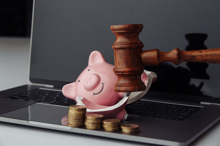 Broken piggy bank with stack of coins and wooden gavel on laptop. Business, finance and bankruptcy conceptの写真素材
