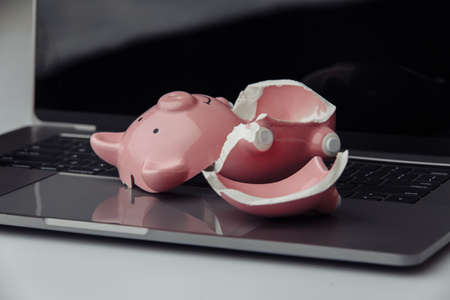 Broken pink piggy bank on a keyboard. Finance and bankruptcy concept