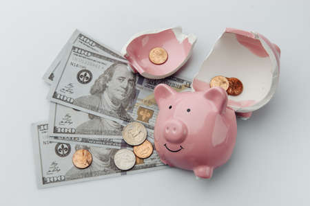 Broken piggy bank with dollar bills on a white background