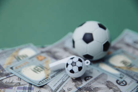 Football Business Concept. Ball and whistle on dollar bills and green background. Soccer gambling money conceptの写真素材