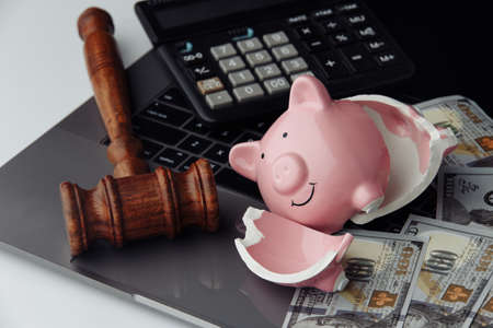 Broken piggy bank, cash and wooden gavel on keyboard. Business and bankruptcy conceptの写真素材