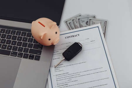Purchase contract for a car with laptop, piggy bank and car keysの写真素材