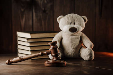 Divorce and alimony concept. Wooden gavel and teddy bear as symbol of childの写真素材