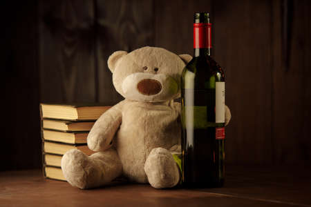 Alcohol and child abuse. Teddy bear as a symbol of childs safety and bottleの写真素材