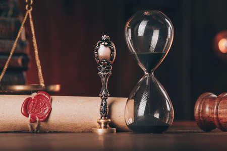 Wooden gavel, hourglass and antique stamp with last will on wooden table close-up