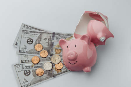 Broken piggy bank with cash on a white backgroundの写真素材