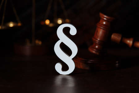 Scales, judge gavel and white paragraph sign close-up in a courtroomの写真素材