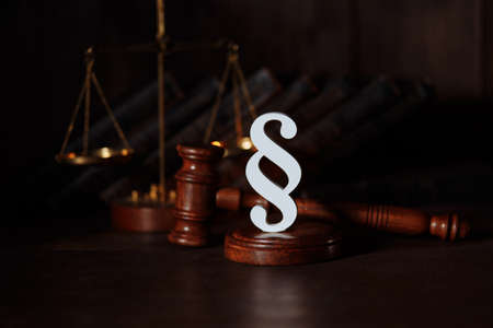 Scales, books, judge gavel and white paragraph sign in a courtroomの写真素材