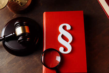 White paragraph symbol on a red book and judge gavel at lawyer office. Top view