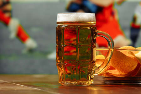 Beer with snack against football field background. Sport and entertainment conceptの写真素材