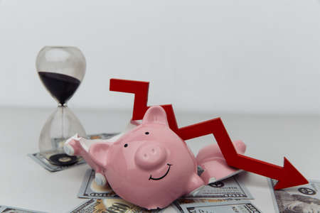 Broken piggy bank with hourglass and red arrow. Investment and bankruptcy conceptの写真素材