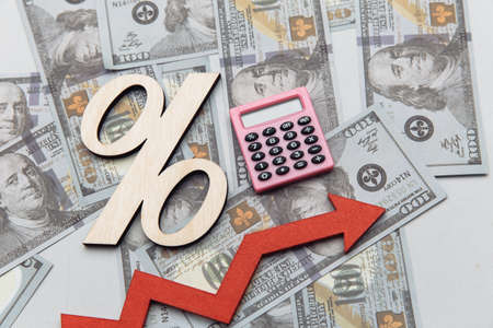 Calculator, arrow up and symbol of percent on dollar banknotes. Investment concept