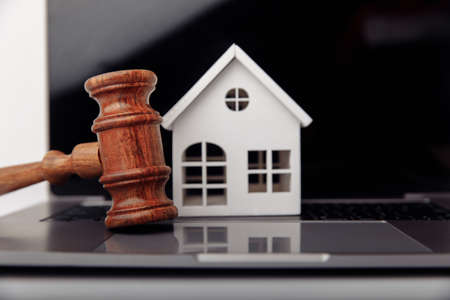 Wooden gavel and house on a laptop close-up. Real estate mortgage auctionの写真素材