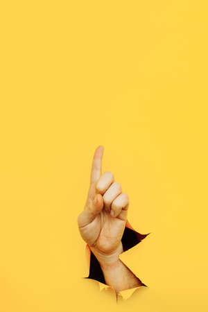 Hand forefinger indicating of the direction isolated on yellow background. Vertical imageの写真素材