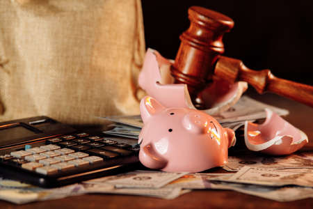 Broken piggy bank with money bag and judge gavel close-up. Economy conceptの写真素材