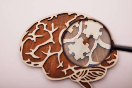 Model of brain and wooden puzzles on a pink background. Mental Health and problems with memory...