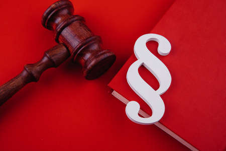 Paragraph symbol is on a book and gavel on red background. Law and justice conceptの写真素材