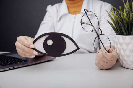 Wooden eye and glasses in doctors hands close-up