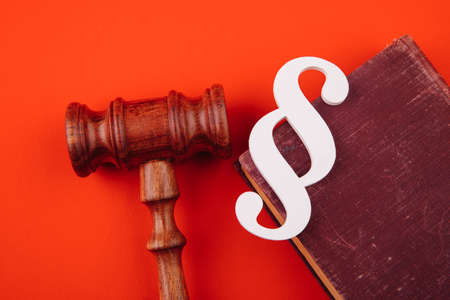 White paragraph symbol is on a law book and gavel on red backgroundの写真素材