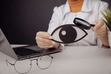 Doctor showing a wooden eye by magnifier. Healthcare conceptの写真素材
