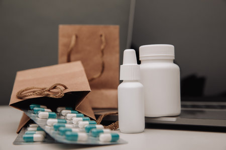 Online pharmacy concept. Pills and spray containers and buff paper bags on the keyboard close-upの写真素材