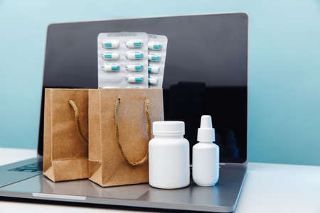 Online medical shopping concept. Paper bags with drugs and pills and conteiners on laptopの写真素材