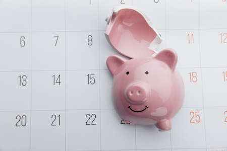 Broken piggy bank on a white calendar background, saving and investment concept. Top viewの写真素材