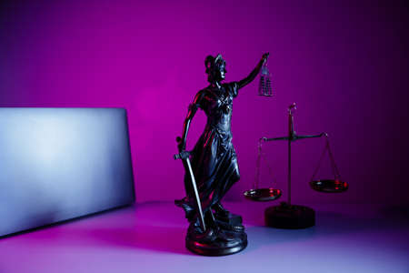 Bronze statue Lady Justice with scales and laptop in notary office on purple background