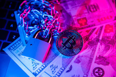 Bitcoin with chain and padlock on dollar cash. Financial fraud themeの写真素材